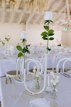 Elegant wedding reception setup with white tablecloths, silverware, and floral centerpieces.
